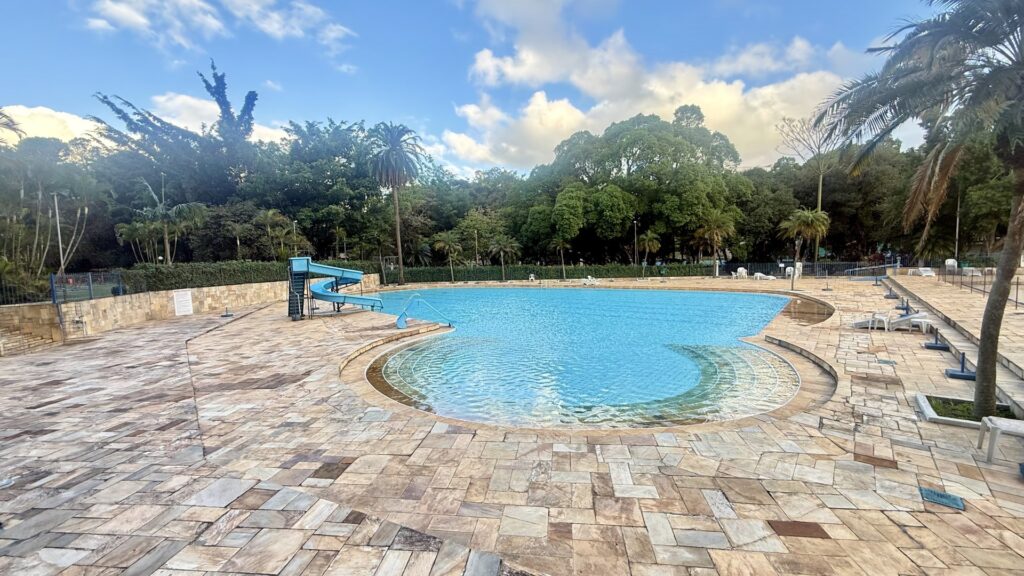 Piscina do condomínio com prainha, toboágua e deck em pedra